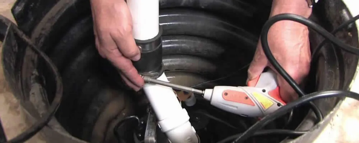 Sump pump installation technician connecting PVC discharge piping in Pittsburgh, PA